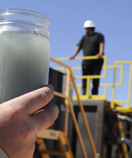 A jar holding waste water from hydraulic fracturing is held up to the light at a recycling site in Midland, Texas, Sept. 24, 2013. The drilling method known as fracking uses huge amounts of high-pressure, chemical-laced water to free oil and natural gas trapped deep in underground rocks. With fresh water not as plentiful companies have been looking for ways to recycle their waste. (AP Photo/Pat Sullivan)
